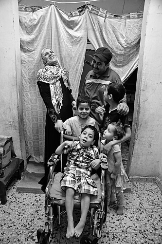Nour sitzt in einem Rollstuhl, er ist von seinen lachenden Familie umgeben.