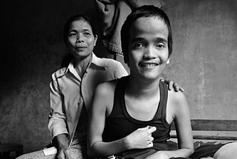 Huyn Thi Le sitzt hinter ihrem Sohn, der lächelt.