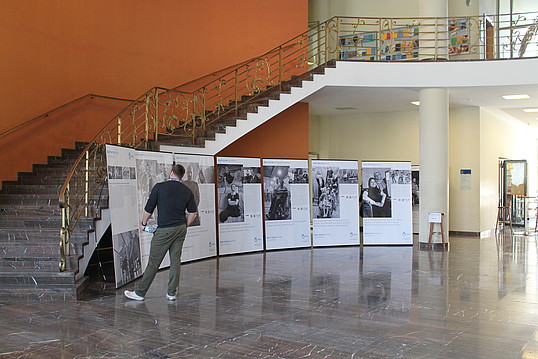 Ein Mann betrachtet die Banner der Ausstellung, die vor einer großen Treppe stehen.