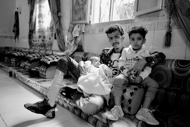 Abdullah sitz mit seinem Baby und seiner Tochter auf einem Sofa