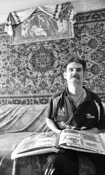 Zynowiy auf einem Sofa, auf den Knien ein Fotoalbum.