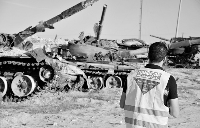 Ein Mann mit Warnweste steht vor mehreren Panzern.