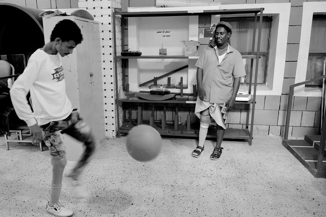 Abdullah und ein anderer Mann spielen Fußball in einem Raum