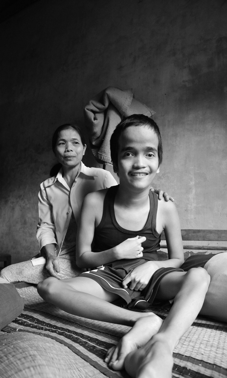 Huyn Thi Le sitzt hinter ihrem Sohn, der lächelt.