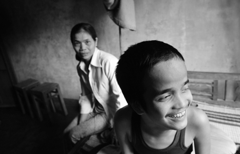 Huyn Thi Le sitzt hinter ihrem Sohn, der lächelt. Sie ist besorgt.